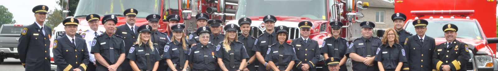Group of Trent Lakes firefighters standing in front of fire trucks.