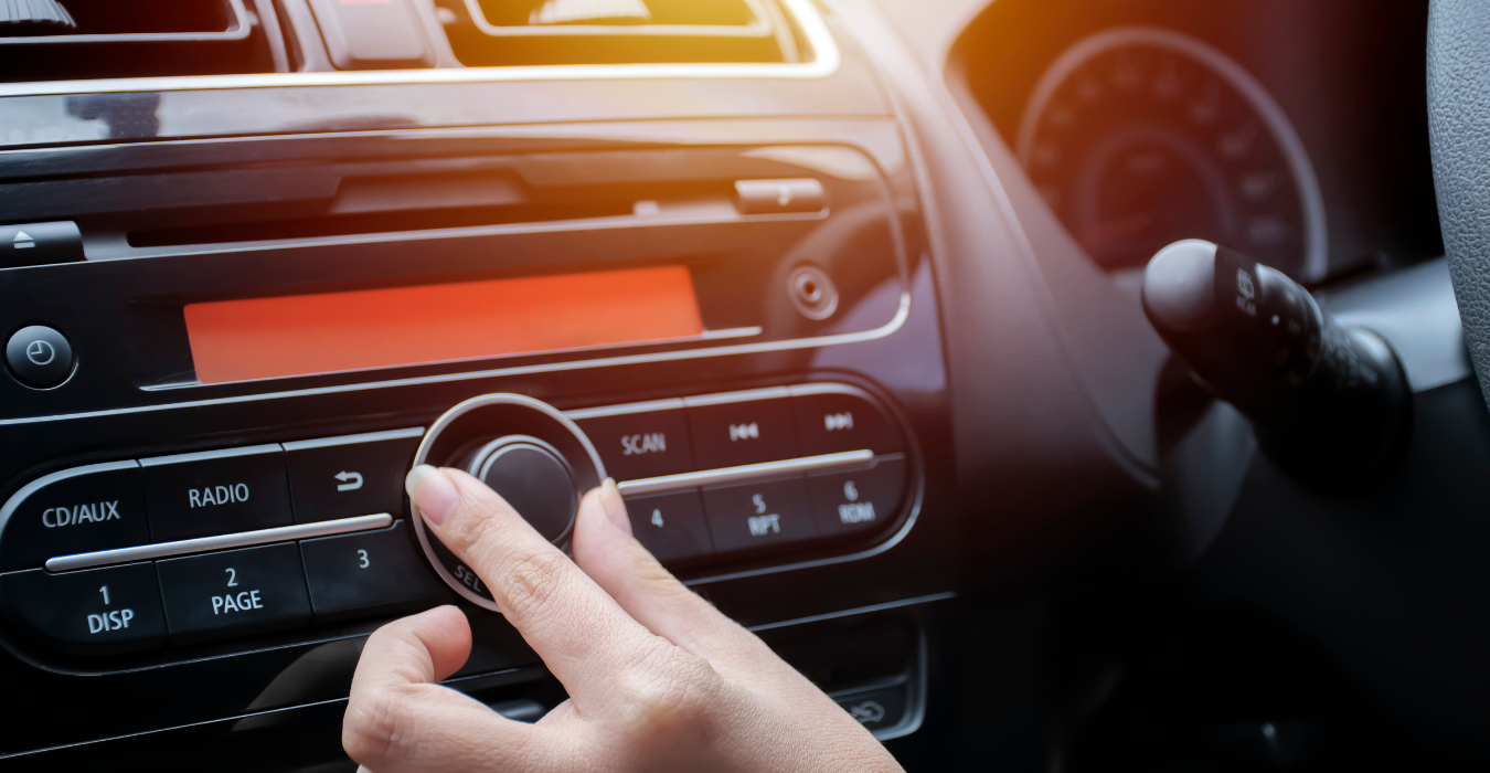 Person tuning the radio dial in a car.