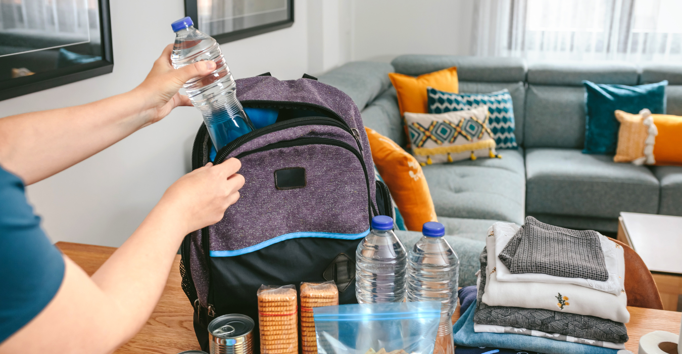 Woman putting water bottle into backpack.